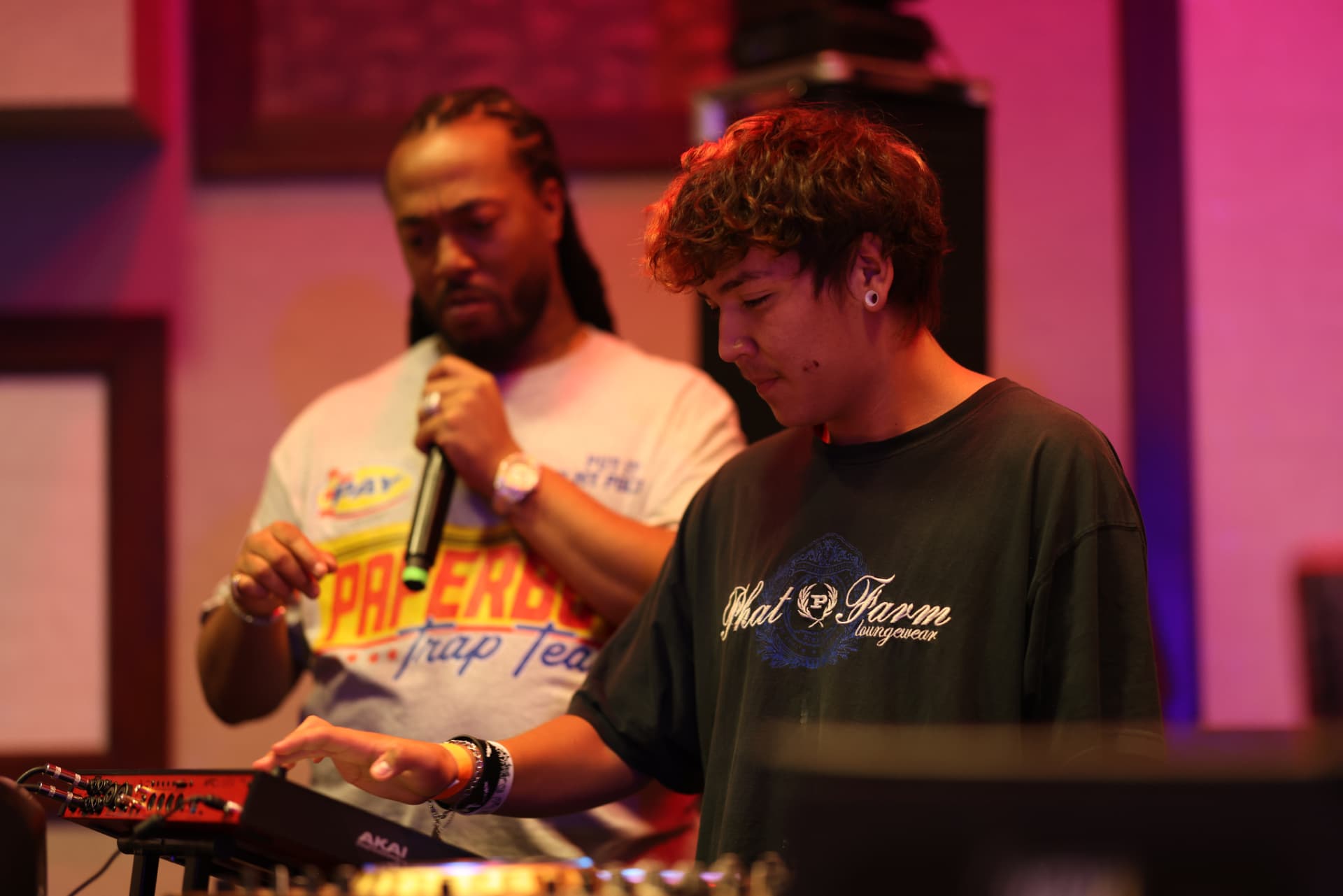 Student building a beat on a music controller while a facilitator supports